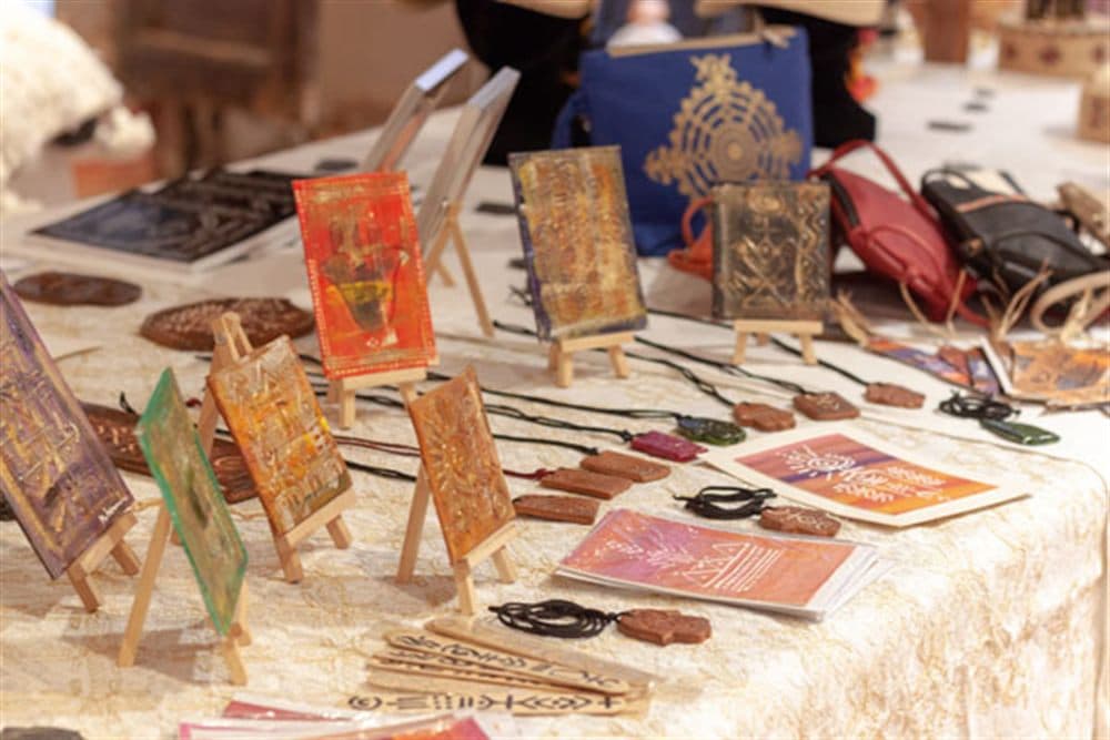 Stand d’artisanat au salon Amlili : miniatures peintes, pendentifs et cartes