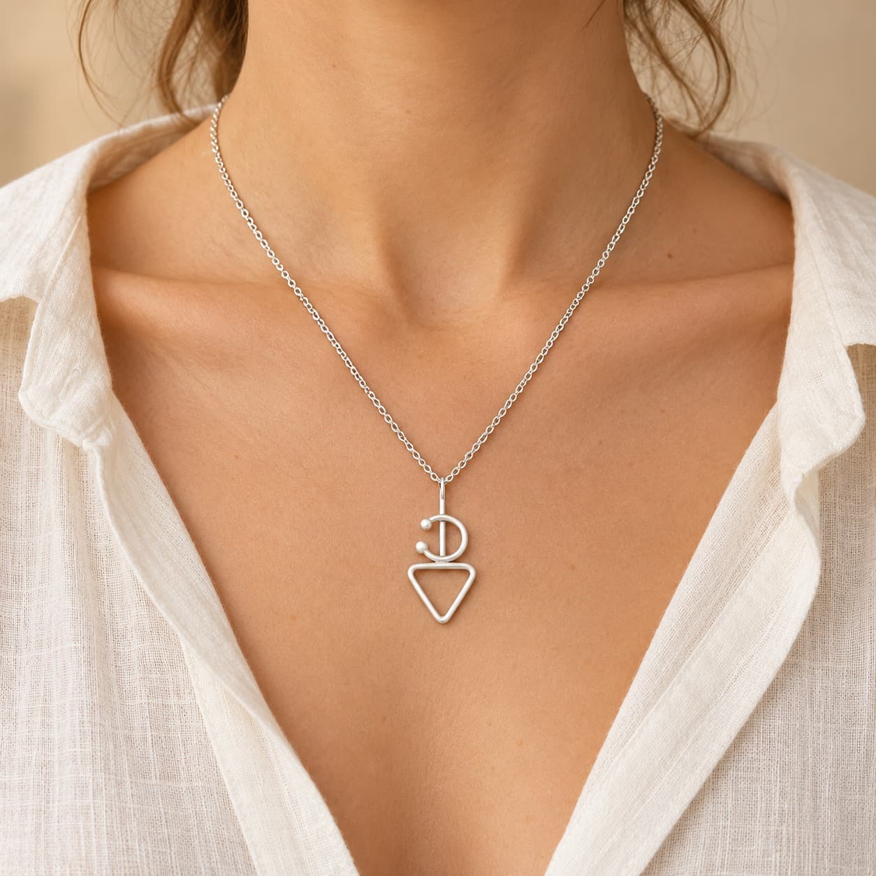 Collier Fibule en argent porté sur peau claire avec une chemise écrue